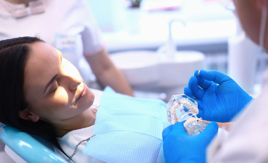 Diş teli tedavisi sonrası kullanılan şeffaf pekiştirme plağı ve modern diş kliniği ortamı.